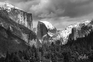 The majestic Half Dome of Yosemite National Park before a winter storm in February surrounded by snow clouds.