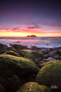 A beautiful sunset at San Francisco's Sutro Bath with moss covered rocks in the foreground.