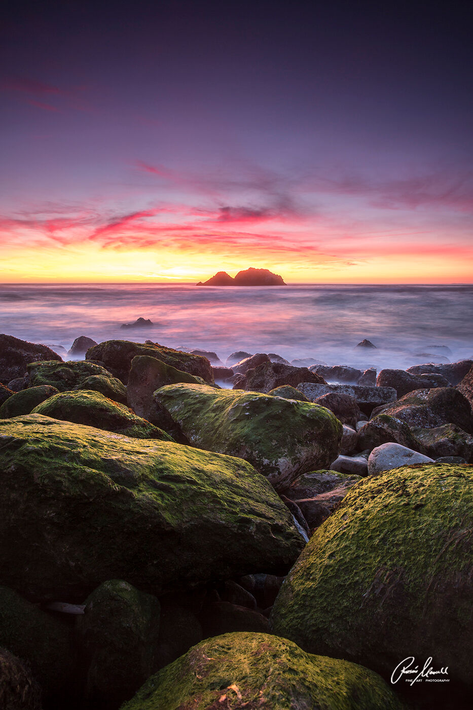 A beautiful sunset at San Francisco's Sutro Bath with moss covered rocks in the foreground.