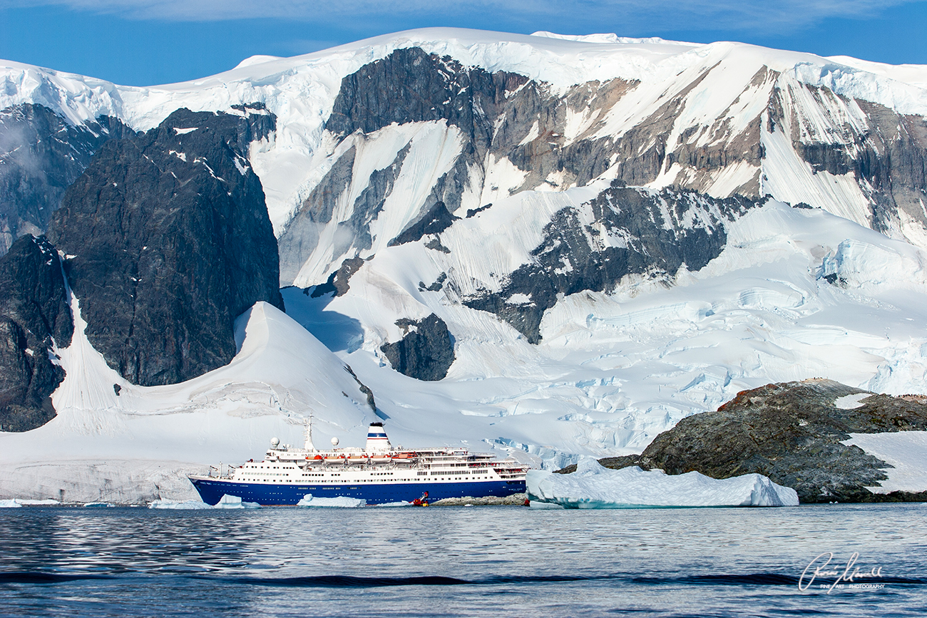 A sunny day near Cuverville Island with the iconic cruise ship MS Marco Polo with an iceberg floating nearby in
Antarctica
